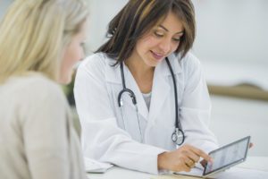 Gynecologist and her patient reading off a tablet