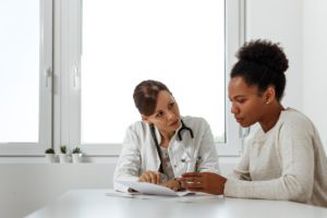 Middle-aged woman at clinic talking with specialist.