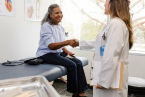 Mature woman smiles as she shakes hands with her gynecologist